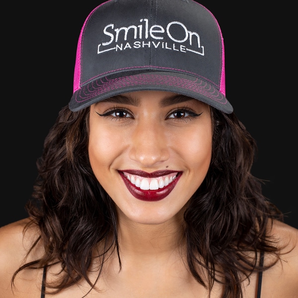 A smiling Smile On Nashville patient wearing a Smile On trucker hat