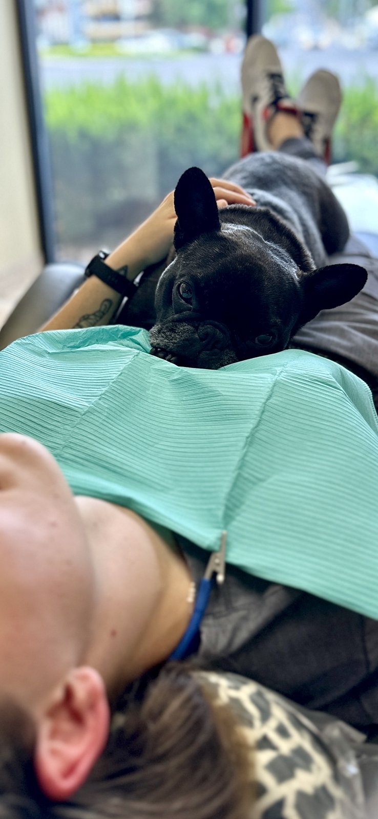 Peewee the therapy dog resting with a patient during a visit at Smile On Nashville